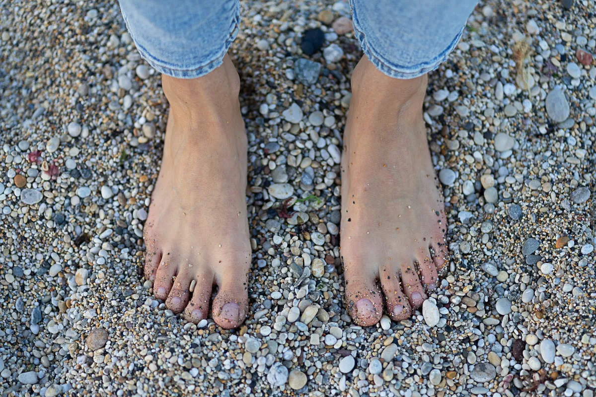 Bare feet resting on a pebbled beach